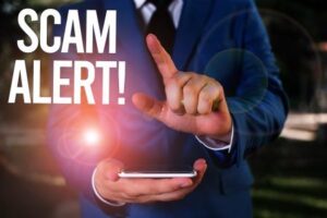 Person in suit holding a smartphone with a 'Scam Alert!' warning, highlighting the importance of staying vigilant against phishing attempts like the Maryland Toll Services scam text