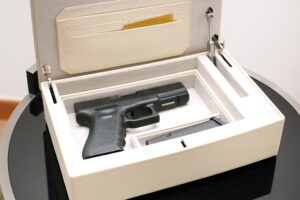 Handgun securely stored in a white lockbox, showcasing proper gun safety storage practices. Huff Insurance advises secure firearm storage to prevent unauthorized access in Maryland homes