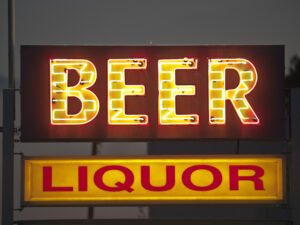 Neon sign displaying the words 'Beer' in bright yellow and 'Liquor' in bold red, representing a liquor store. The sign is illuminated against a dark background, conveying the need for Liquor Store Insurance to protect such businesses.